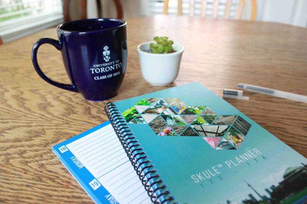 Skule Planner agenda book set on a table with a mug of coffee, a pen, and a plant